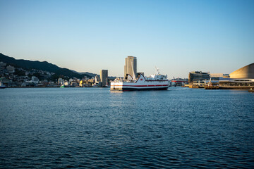 Naklejka premium 港を行くフェリーと街並み