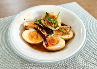 This flavorful dish showcases halved boiled eggs served in a rich, soy-based sauce with a hint of spice.