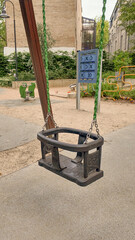 Modern playground with yellow slide and black tunnel tube structure in urban park. Sunny day, city skyscrapers in background. Children's outdoor play area