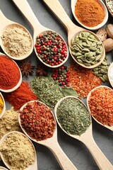 Many different spices in spoons on grey table, flat lay