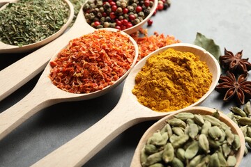 Many different spices in spoons on grey table, closeup