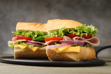 Pieces of tasty baguette sandwich with ham, cheese and vegetables on table against grey background, closeup