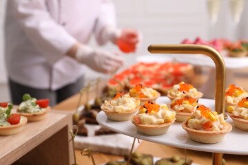 Chef arranging appetizers on buffet table, selective focus
