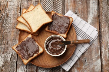 Tasty chocolate butter, slices of bread and knife on wooden table, top view