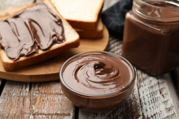 Tasty chocolate butter and slices of bread on wooden table, closeup