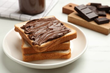 Tasty chocolate butter and slices of bread on white table, closeup