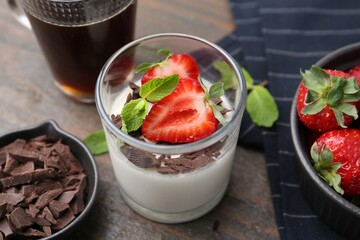 Tasty panna cotta with chocolate, strawberries, mint, vanilla pods and tea on wooden table, above...