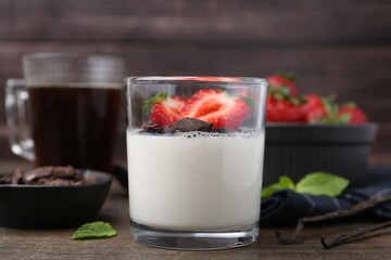 Tasty panna cotta with chocolate, strawberries, mint, vanilla pods and tea on wooden table, closeup