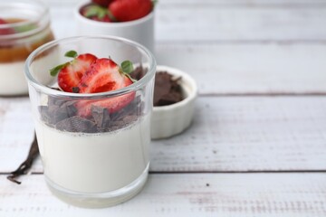 Tasty panna cotta with chocolate, strawberries and vanilla on white wooden table, closeup. Space...