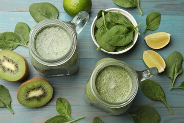 Tasty smoothie in mason jars, spinach leaves, kiwi and lime on light blue wooden table, flat lay