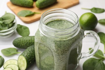 Tasty smoothie in mason jar, spinach leaves and cucumber on white table, closeup