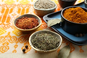 Many different aromatic spices in bowls on table with cloth, closeup