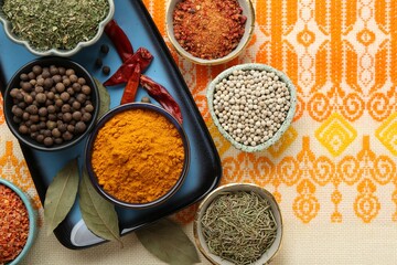 Many different aromatic spices in bowls on table with cloth, flat lay. Space for text