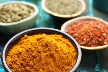 Many different aromatic spices in bowls on table with cloth, closeup