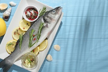 Fresh raw seabass fish with spices on blue wooden table, flat lay and space for text. Seafood...