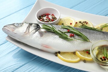 Fresh raw seabass with spices on blue wooden table, closeup. Fish and seafood delicacies