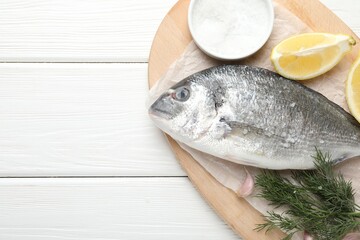 Fresh raw dourade fish with spices on white wooden table, top view and space for text. Seafood...