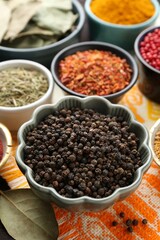 Different aromatic spices on orange tablecloth, closeup