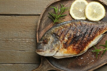 Homemade seafood dish. Tasty roasted dorado fish and spices on wooden table, top view. Space for text