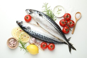 Fresh raw mackerels and spices on white table, flat lay. Seafood delicacies