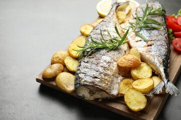 Tasty roasted mackerels with spices and vegetables on grey table, closeup. Homemade seafood dish