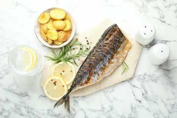 Tasty roasted mackerel served with spices and potatoes on white marble table, flat lay. Homemade...
