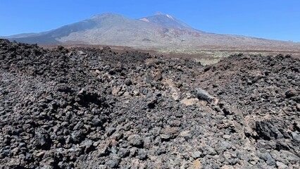 Embarking on an adventure in a volcanic landscape of dark lava rocks and a breathtaking mountain...