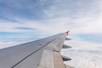 View from the airplane window at a beautiful cloudy sky and the airplane wing