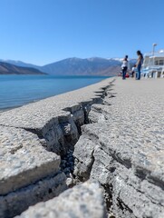Cracked concrete walkway by a lake