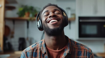 Happy man wearing wireless headphones and listening to music in kitchen