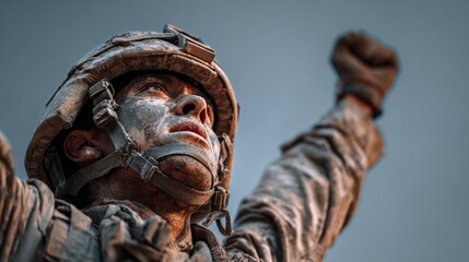 Victorious male soldier raising arm triumphantly in mud-stained uniform