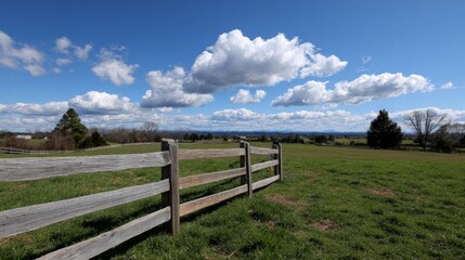 Fototapeta premium Rustic fence with lush green field and dramatic cloudy sky in countryside landscape