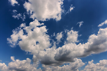 Puffy clouds drift across bright blue sky, creating calm peaceful atmosphere during sunny day.