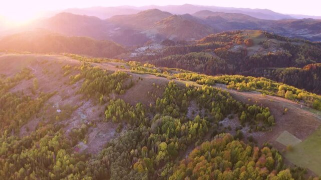 Ukraine, drone, flight in the Carpathians early in the autumn morning at sunrise near the city of Kosiv. Bright forests and dwellings of the Hutsul highlanders on the glades
