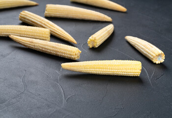 Baby corn scattered on a dark background, close -up