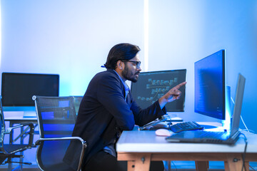 Focused Indian male AI developer coding a complex machine learning algorithm late at night. A...