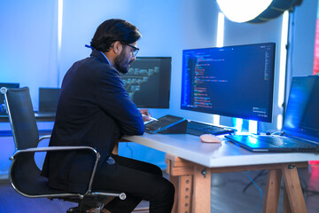 Focused Indian male AI developer coding a complex machine learning algorithm late at night. A...