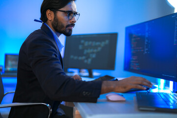 Focused Indian male AI developer coding a complex machine learning algorithm late at night. A...