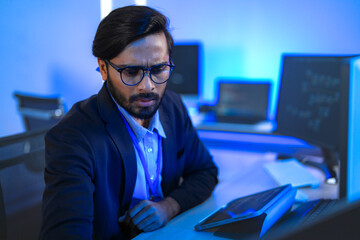 Focused Indian male AI developer coding a complex machine learning algorithm late at night. A...