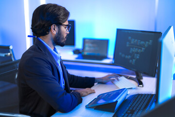 Focused Indian male AI developer coding a complex machine learning algorithm late at night. A...