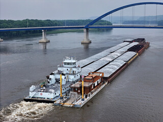 Aerial view of a large barge traveling under the Dale Gardner Veterans Memorial Bridge at Savanna illinois on the Mississippi River