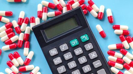 Calculator and Red and White Capsules on Blue Background