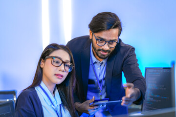 Asian female AI programmer and Indian male data analyst reviewing code on a monitor. Diverse tech...