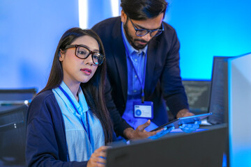 Asian female AI programmer and Indian male data analyst reviewing code on a monitor. Diverse tech...