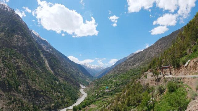 4K shot of river Chenab flowing between the two Himalayan mountain peaks with clouds above it as seen on the way towards Udaipur in Pattan valley, Lahaul, Himachal Pradesh, India. Scenic background.