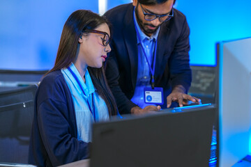 Asian female AI programmer and Indian male data analyst reviewing code on a monitor. Diverse tech...