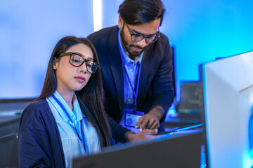 Asian female AI programmer and Indian male data analyst reviewing code on a monitor. Diverse tech...