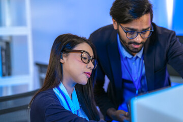 Asian female AI programmer and Indian male data analyst reviewing code on a monitor. Diverse tech...