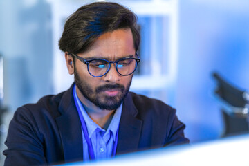 Focused Indian male AI developer coding a complex machine learning algorithm late at night. A...