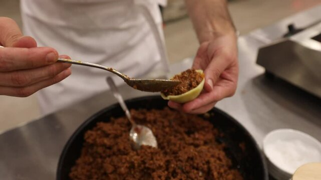 Chef stirs seasoned minced meat. Stuffed pasta shells with meat filling simmer in bubbling tomato sauce. This hearty, delicious Italian meal is perfect for a family dinner.